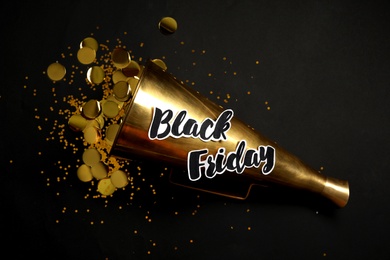 Photo of Phrase Black Friday, horn and confetti on dark background, flat lay
