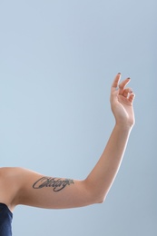 Female arm with tattoo on color background