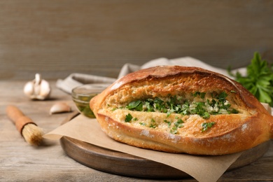 Photo of Delicious homemade garlic bread with herbs on wooden table