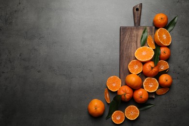 Photo of Fresh ripe tangerines and space for text on dark grey table, flat lay. Citrus fruit