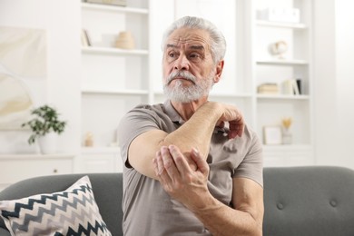 Arthritis symptoms. Man suffering from pain in elbow at home