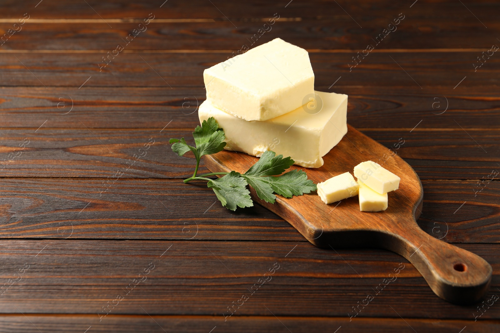 Photo of Tasty butter and parsley on wooden table. Space for text