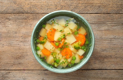 Photo of Bowl of fresh homemade vegetable soup on wooden background, top view