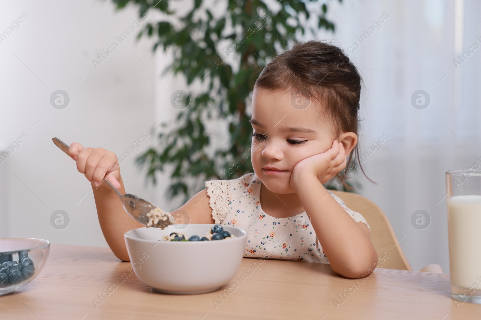 Photo of Cute little girl refusing to eat her breakfast at home