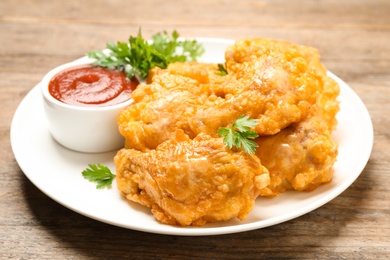 Photo of Tasty deep fried chicken pieces served on wooden table