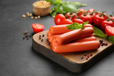 Photo of Fresh raw vegetarian sausages and vegetables on black table, closeup