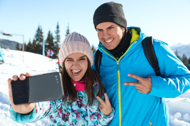 Happy couple taking selfie in mountains. Winter vacation