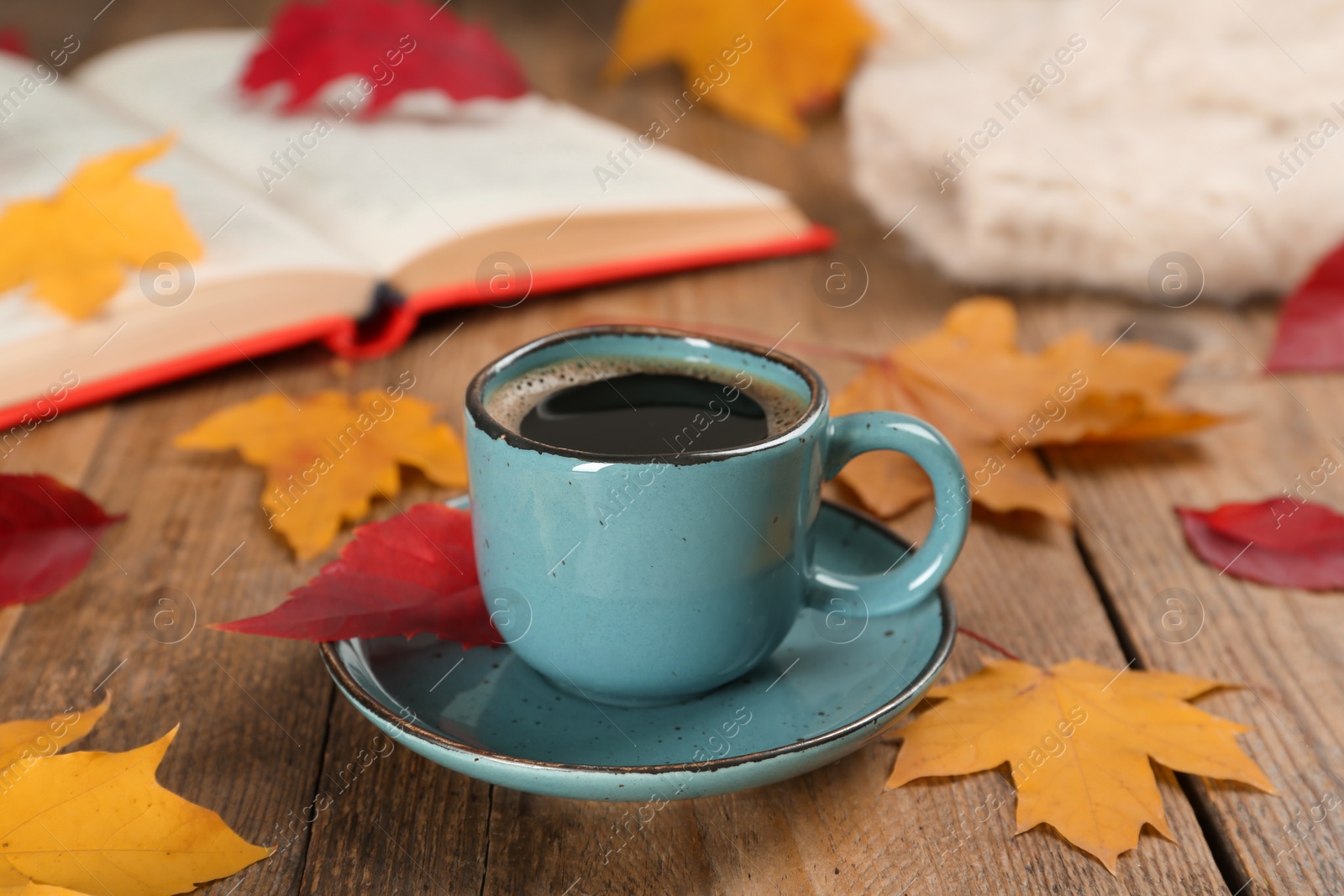 Photo of Cup of hot coffee and autumn leaves on wooden table