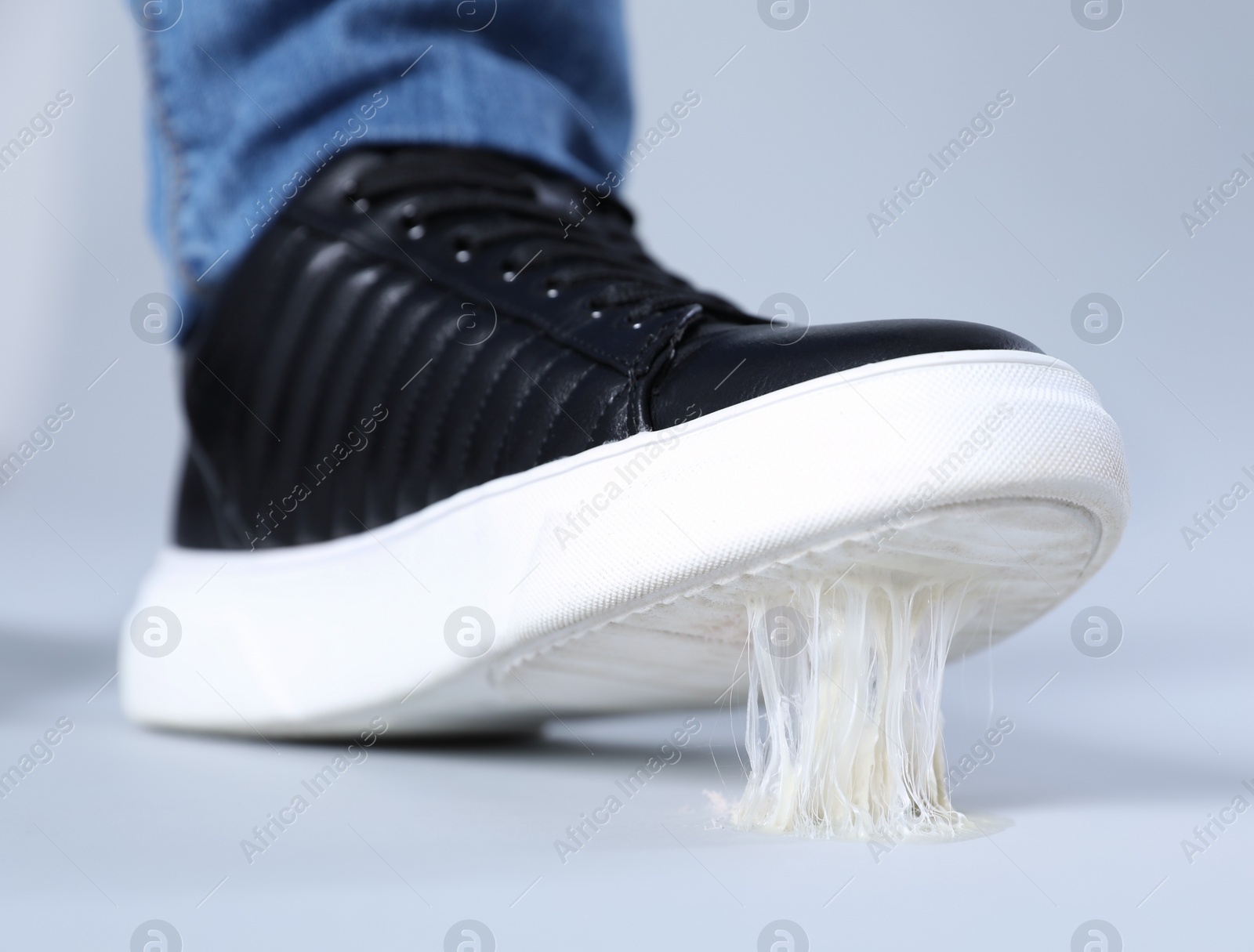 Photo of Man stepping into chewing gum on light grey background, closeup