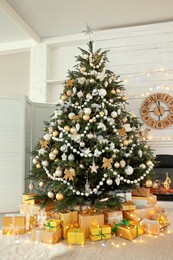 Photo of Decorated Christmas tree with gift boxes and fireplace in room