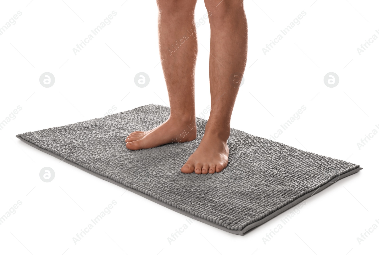 Photo of Man standing on soft grey bath mat against white background, closeup