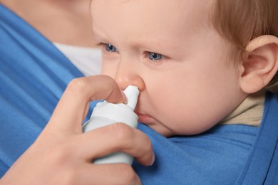 Photo of Mother helping her baby to use nasal spray, closeup