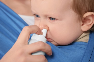 Mother helping her baby to use nasal spray, closeup