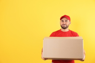 Portrait of man in uniform carrying carton box on color background. Posture concept