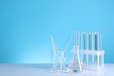 Photo of Laboratory analysis. Different glassware on table against light blue background, space for text