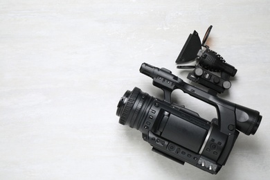 Modern video camera with flashlight on light grey background, top view. Space for text