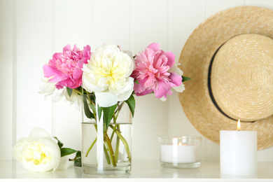 Bouquet of beautiful peonies in vase and candles on white table