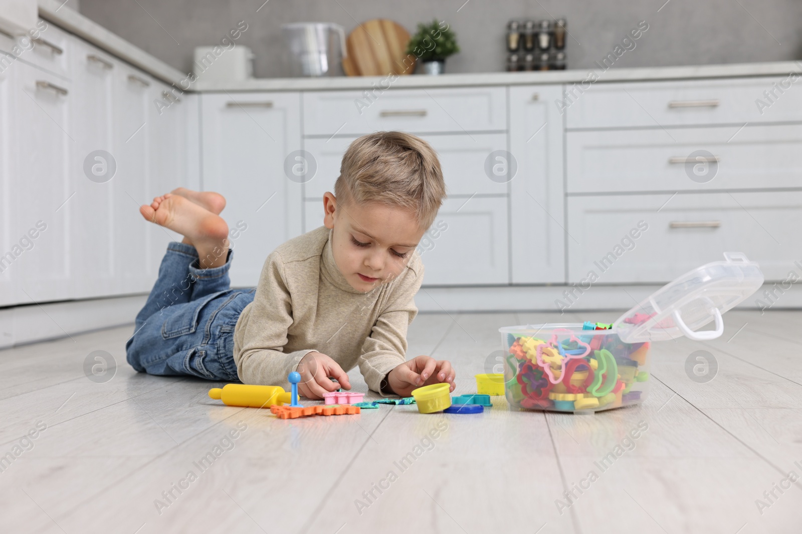 Photo of Cute little boy playing on warm floor in kitchen. Heating system