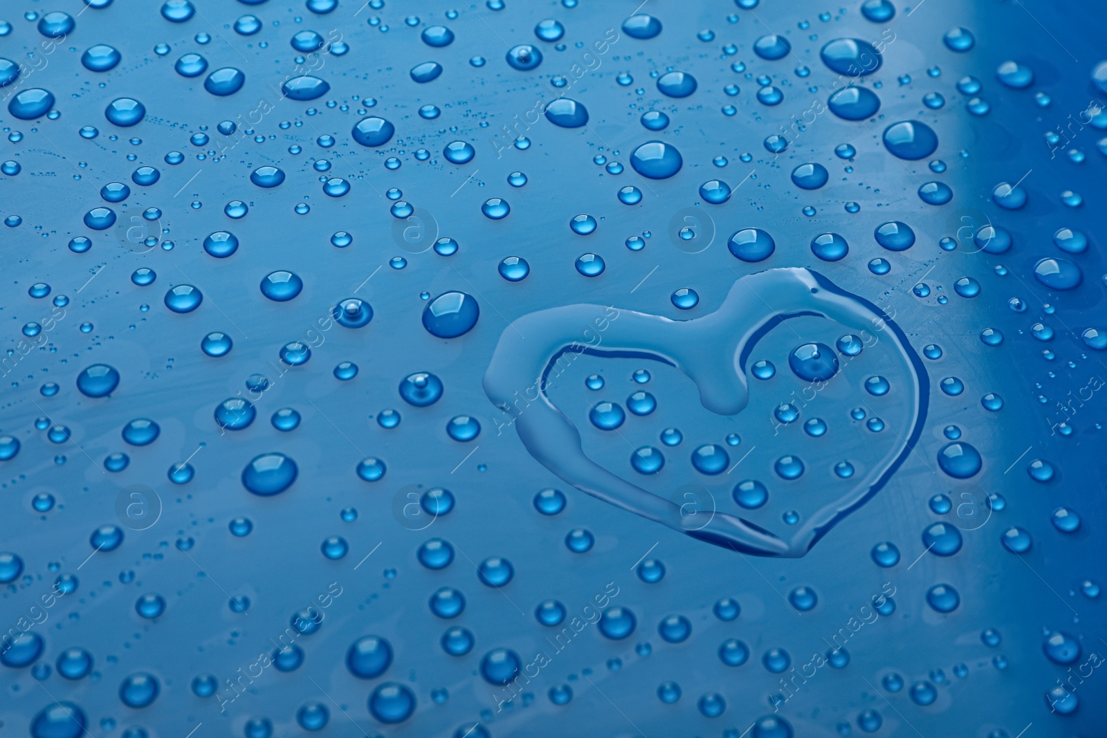 Photo of Heart shape of water and drops on blue background