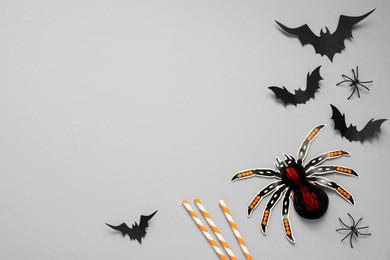 Photo of Flat lay composition with paper bats, spiders and cocktail straws on light grey background, space for text. Halloween decor