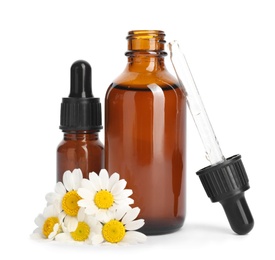 Chamomile flowers and cosmetic bottles of essential oil on white background