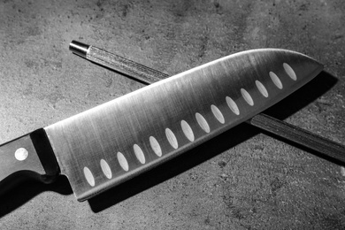 Santoku knife and sharpener on grey background