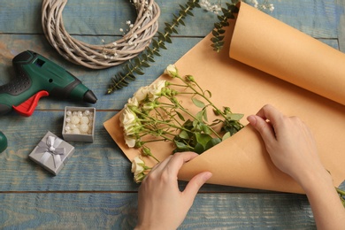 Photo of Female florist making beautiful bouquet at table, top view