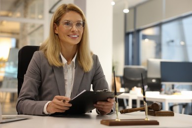 Smiling lawyer with clipboard working at table in office