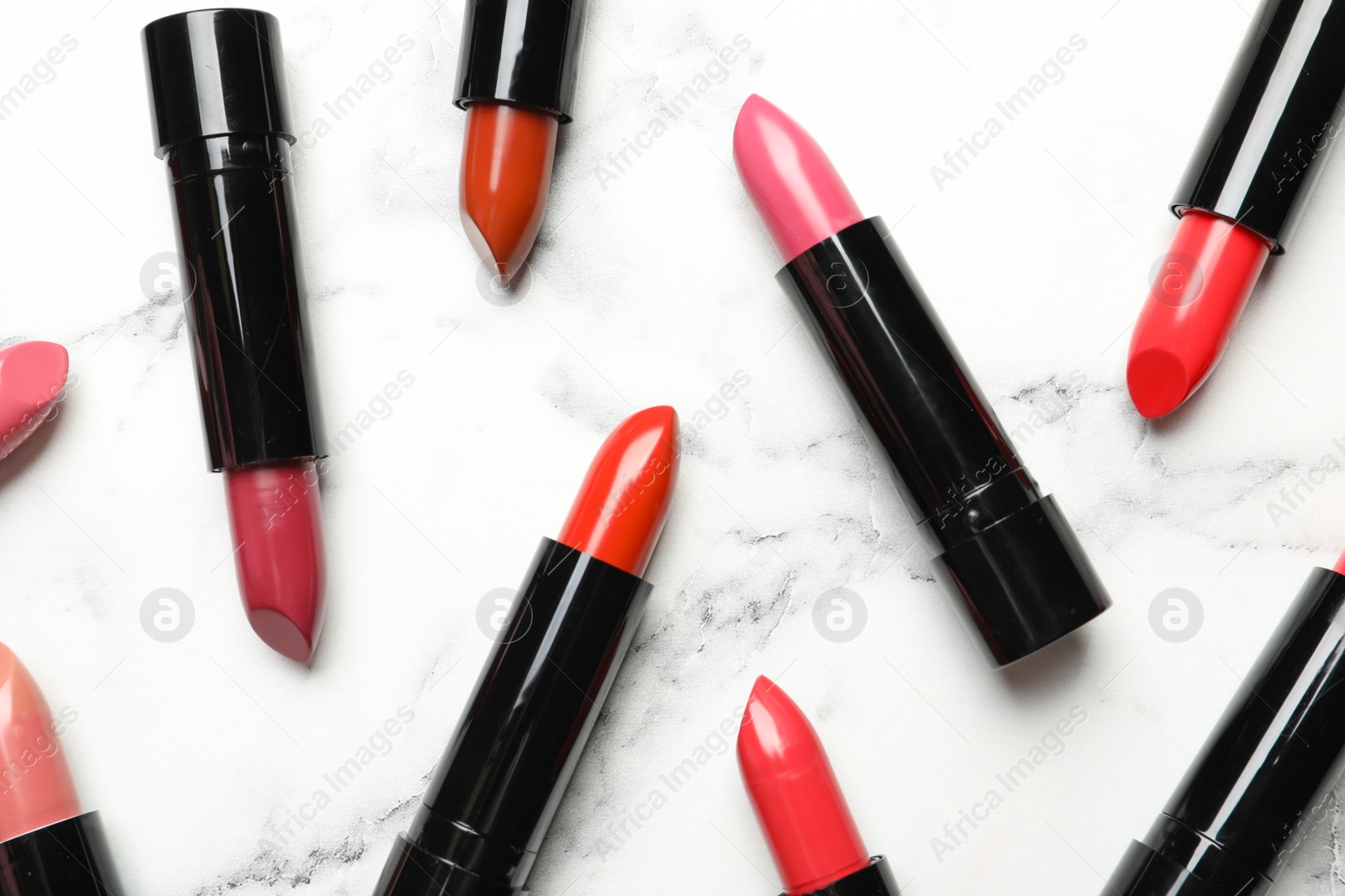 Photo of Different lipsticks on marble background, flat lay