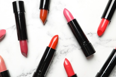 Different lipsticks on marble background, flat lay