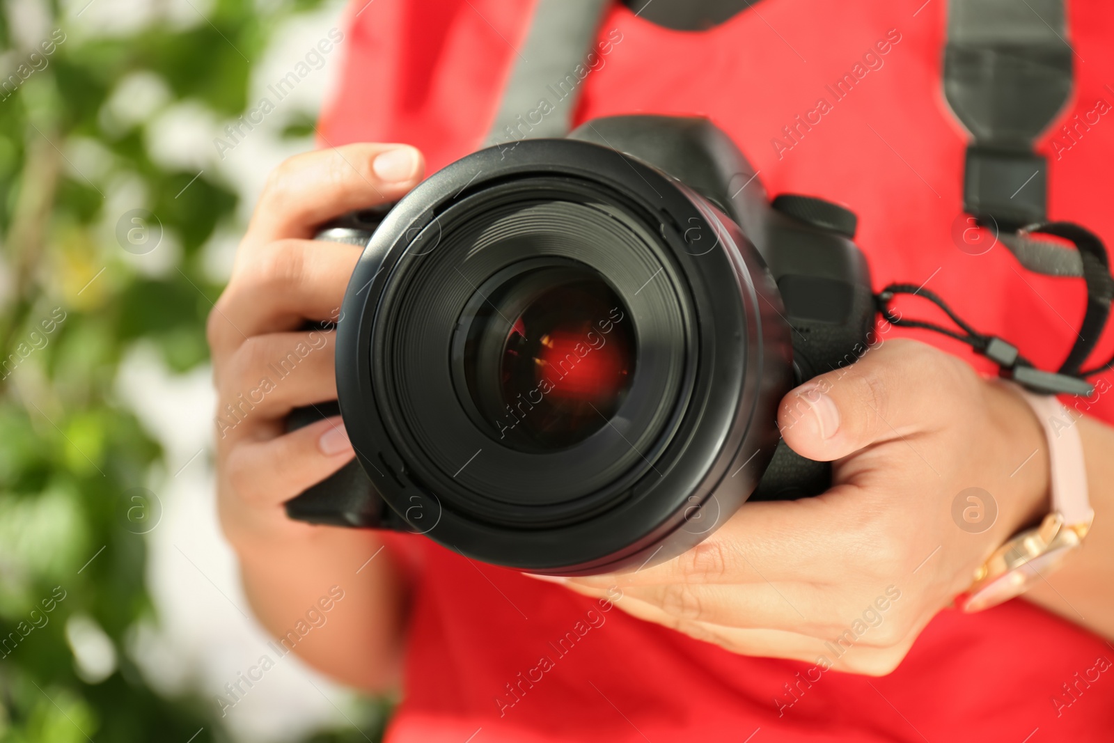 Photo of Female photographer with professional camera on blurred background, closeup