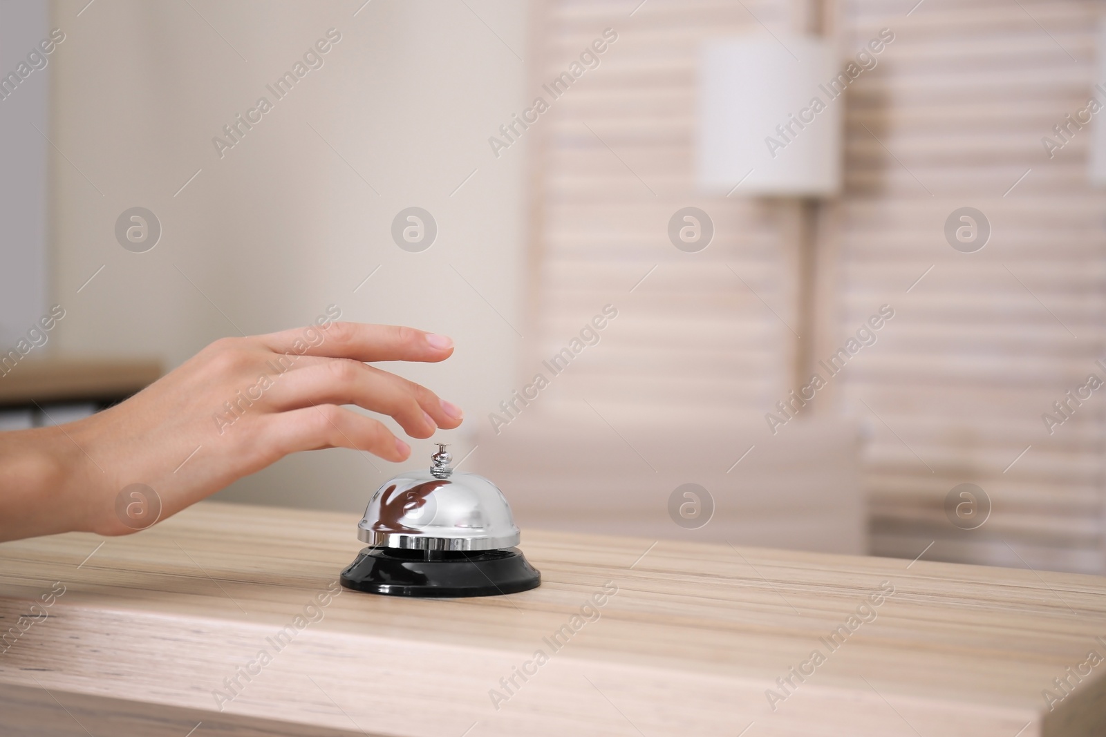 Photo of Woman ringing service bell on reception desk in hotel, closeup