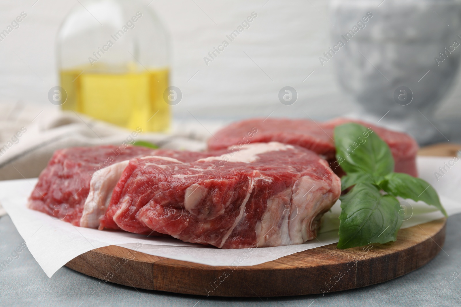 Photo of Fresh raw cut beef and basil leaves on grey table, closeup