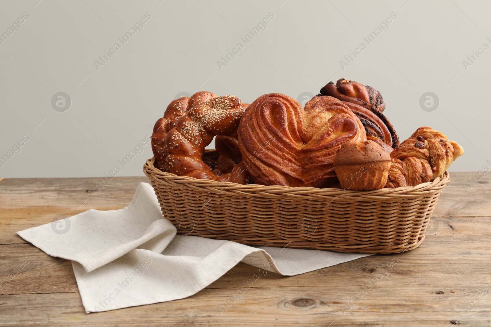 Photo of Wicker basket with different tasty freshly baked pastries on wooden table