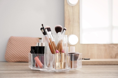 Organizer with cosmetic products for makeup on table near mirror