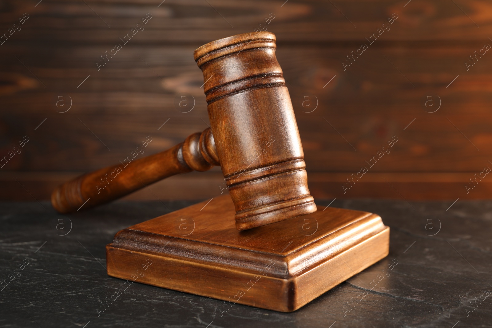 Photo of Wooden gavel and sound block on dark textured table, closeup