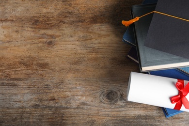 Photo of Flat lay composition with graduation hat and student's diploma on wooden table, space for text