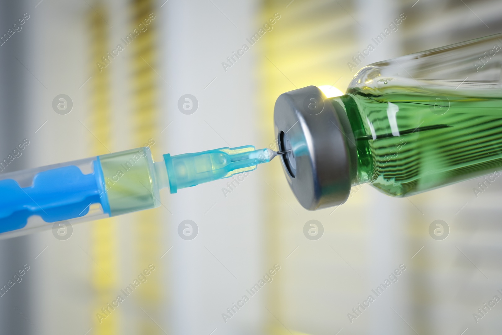 Photo of Filling syringe with medication from vial against blurred background, closeup. Vaccination and immunization