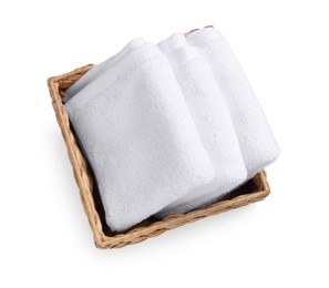 Photo of Soft folded terry towels in wicker basket isolated on white, top view
