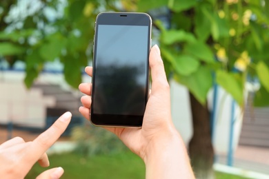 Woman holding modern smartphone outdoors. Mock up with space for text