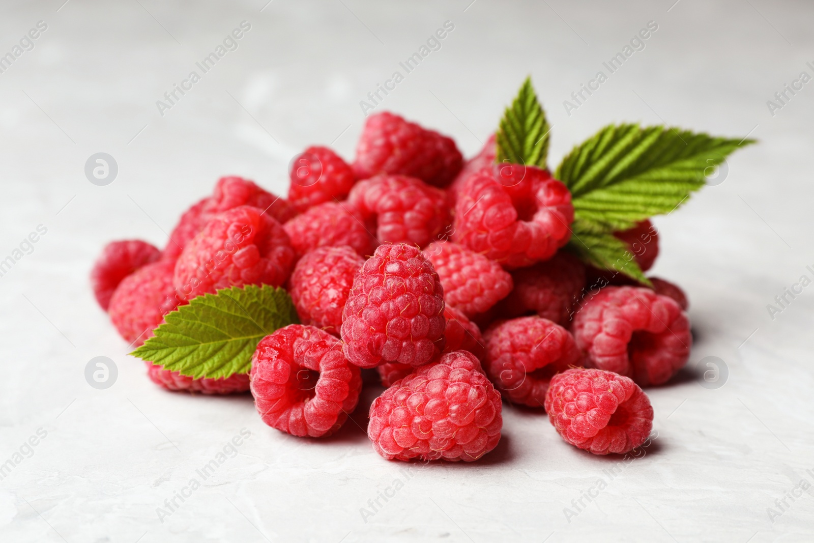 Photo of Heap of delicious ripe raspberries on light marble background, closeup