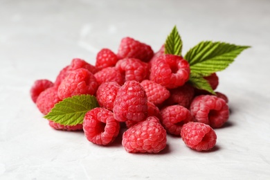 Heap of delicious ripe raspberries on light marble background, closeup