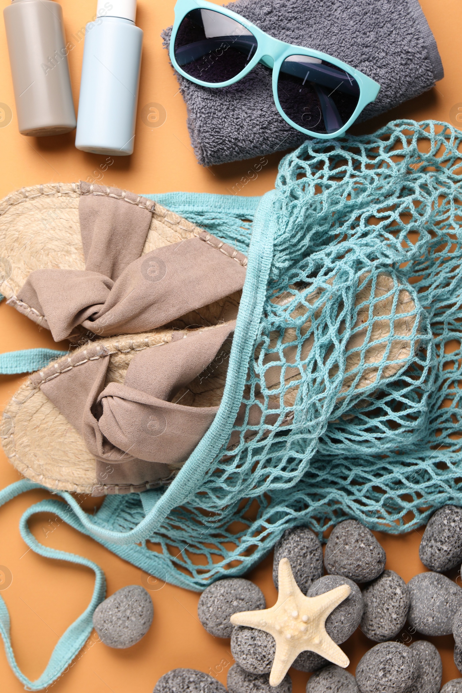 Photo of String bag and different beach accessories on pale orange background, flat lay