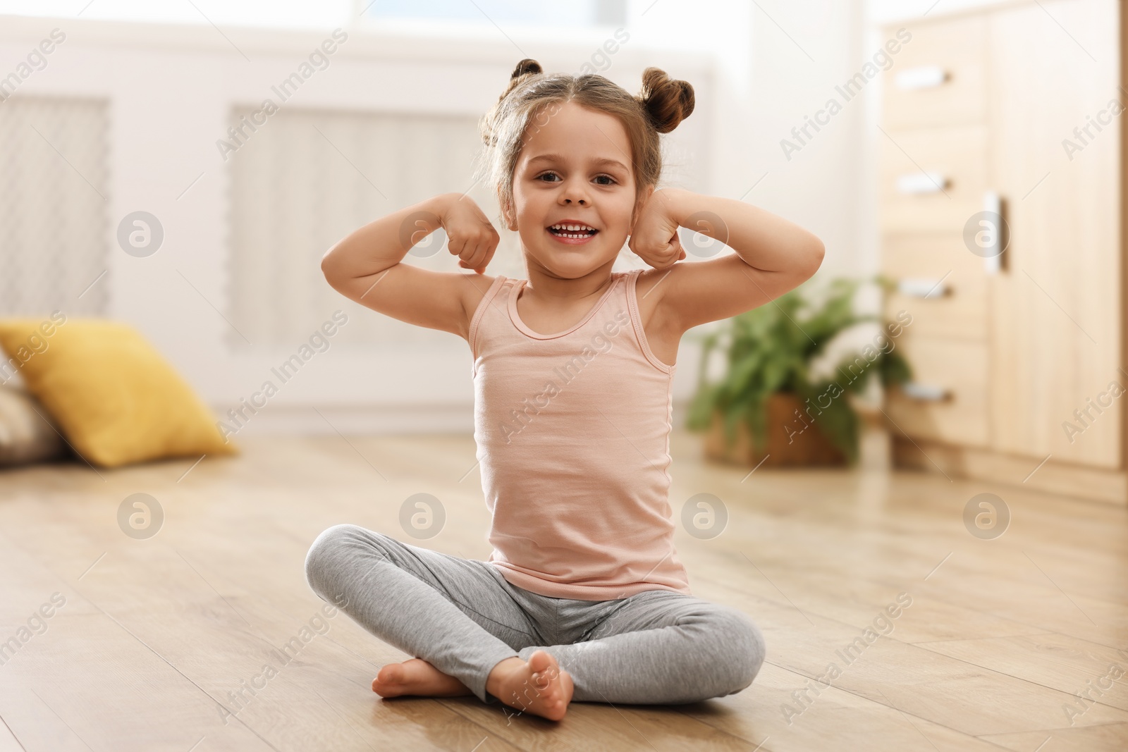 Photo of Little cute girl practicing yoga on floor at home