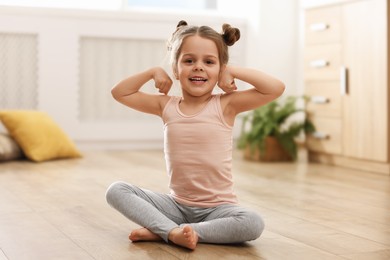 Little cute girl practicing yoga on floor at home