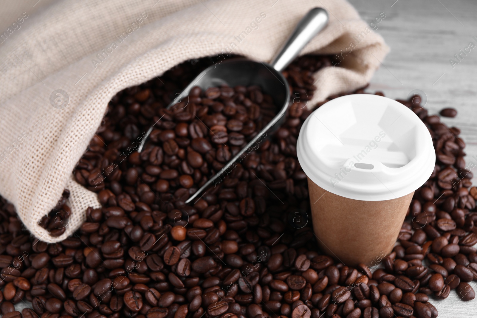 Photo of Coffee to go. Paper cup, roasted beans and scoop on table, space for text