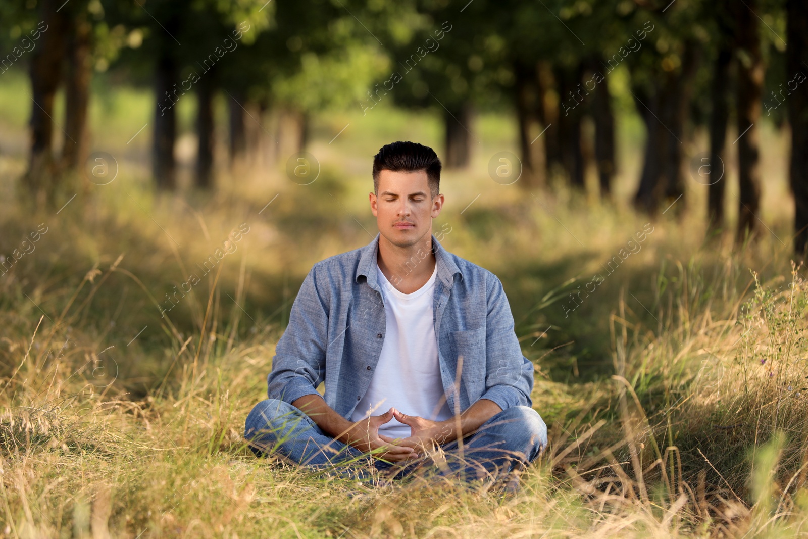 Photo of Man meditating in forest on sunny day