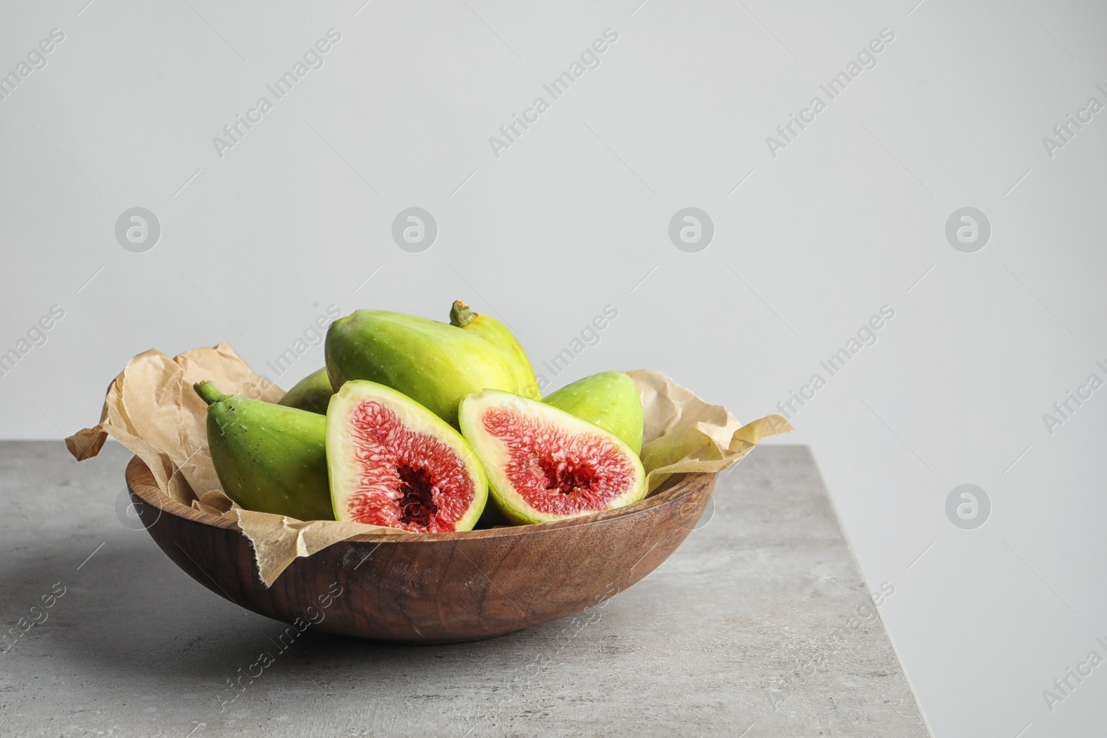 Photo of Bowl with fresh ripe figs on gray table. Space for text