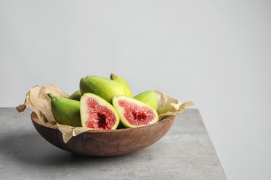 Photo of Bowl with fresh ripe figs on gray table. Space for text