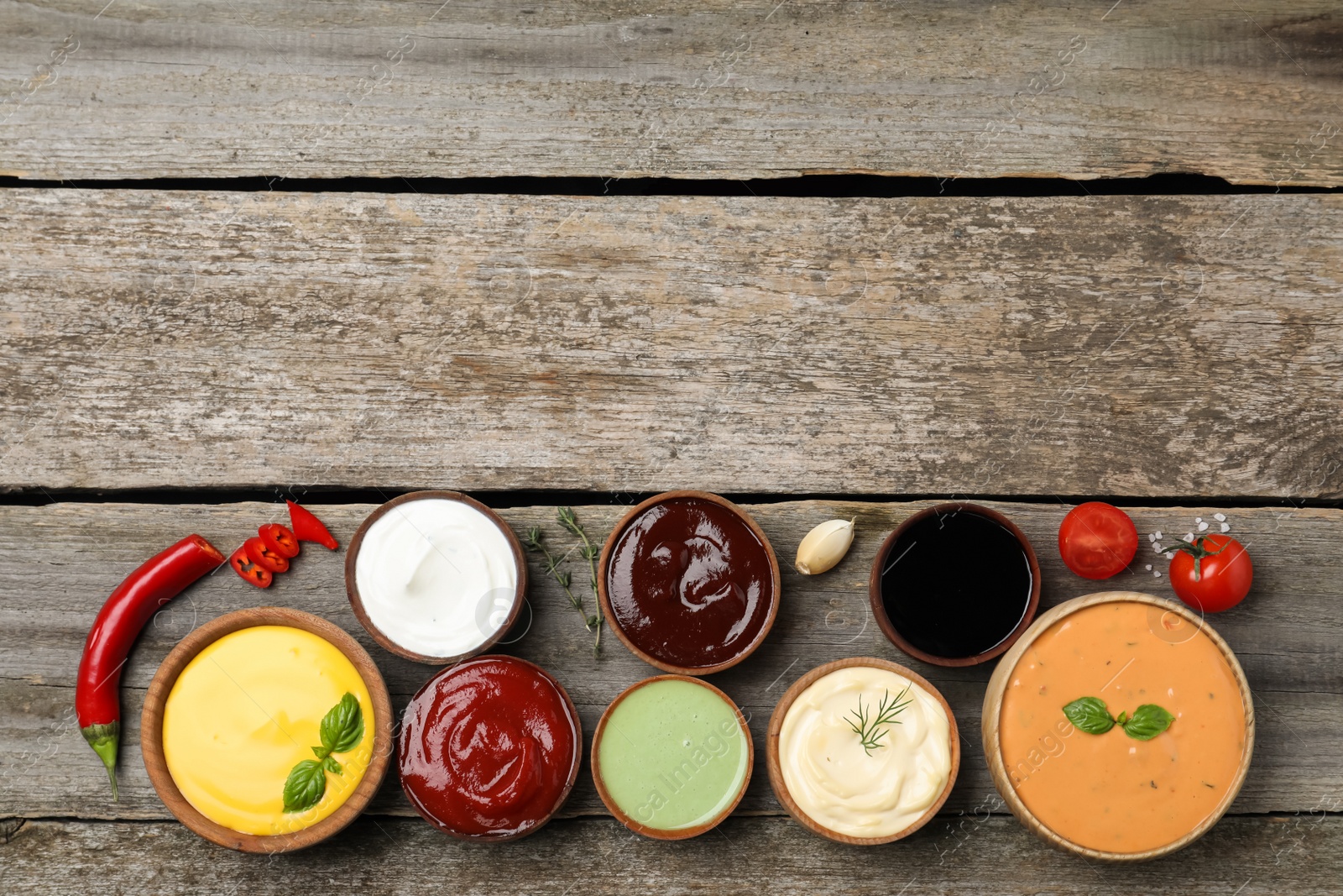 Photo of Many different sauces on wooden table, flat lay. Space for text